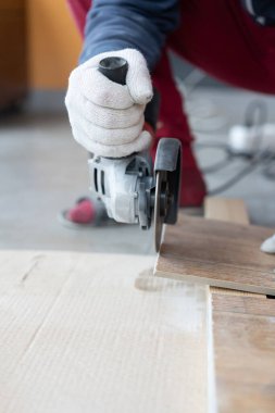 Tamir ve dekorasyon. Bir adam seramik fayansları öğütücüyle keser..