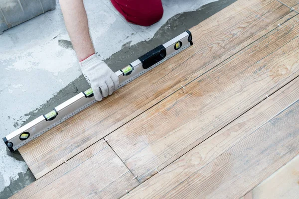 Réparation et décoration. le carreleur pose les carreaux de porcelaine sur le sol de l'appartement — Photo