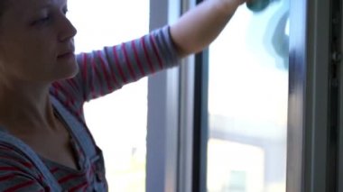Pencereyi temizleyen genç kadın, ağır çekimde.
