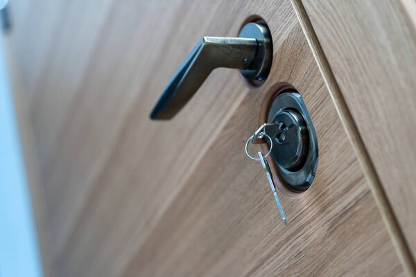 door lock with key and handle close up, beautiful modern wooden entrance door to the apartment