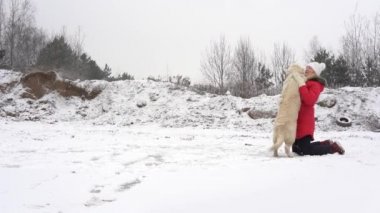 Güzel, yavaş çekim videosu. Kışın buz pistinde köpeğiyle eğlenen bir kadın.