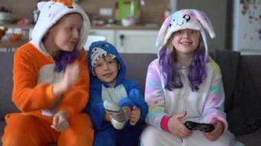 Kigurumi 'deki mutlu aile evdeki oturma odasında TV' de oyun konsolu oynuyor.