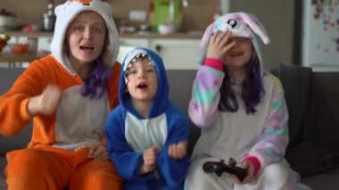 Kigurumi 'deki mutlu aile evdeki oturma odasında TV' de oyun konsolu oynuyor.