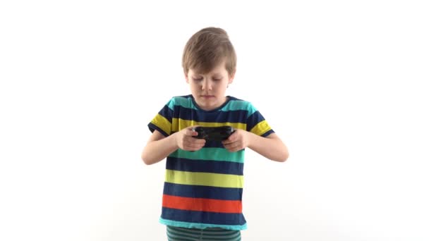 Маленький мальчик в студии на белом фоне играет джойстик в видеоиграх — стоковое видео