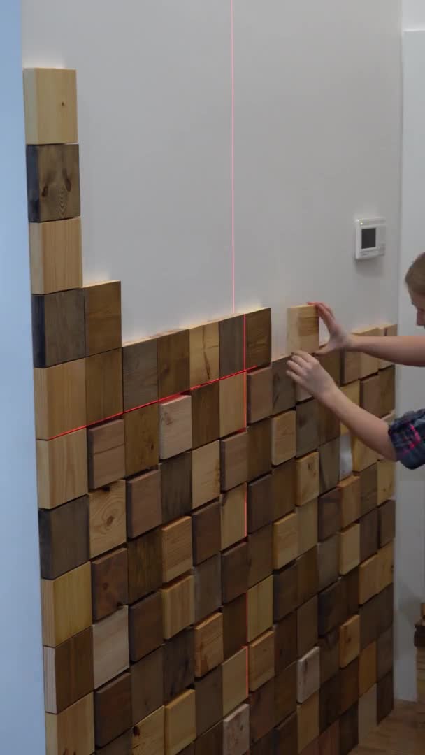 Originele moderne reparatie in een loft stijl. vrouw versiert een muur in een appartement met houten stukken. verticale video — Stockvideo