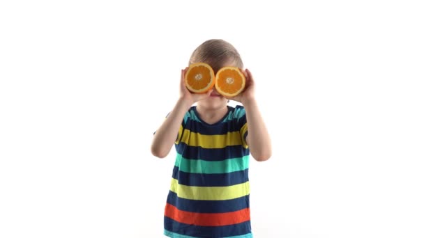 Menino posando em estúdio em um fundo branco com laranja corte em vez de olhos — Vídeo de Stock