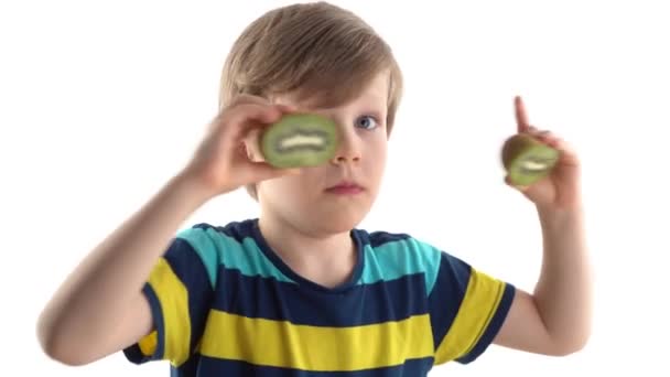 Little boy posing in studio on a white background with cut kiwi instead of eyes — Stock Video