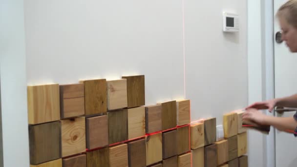 Πρωτότυπη σύγχρονη επισκευή σε στυλ loft. γυναίκα διακοσμεί έναν τοίχο σε ένα διαμέρισμα με ξύλινα κομμάτια — Αρχείο Βίντεο