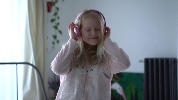 Modern life of generation Z. teenage girl in pajamas and headphones in the room on the bed listens to music from a smartphone. — 图库视频影像