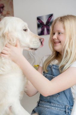 Evcil hayvanlara ilgi ve sevgi. Evde genç bir kız Golden Retriever büyük bir köpekle kucaklaşıyor.