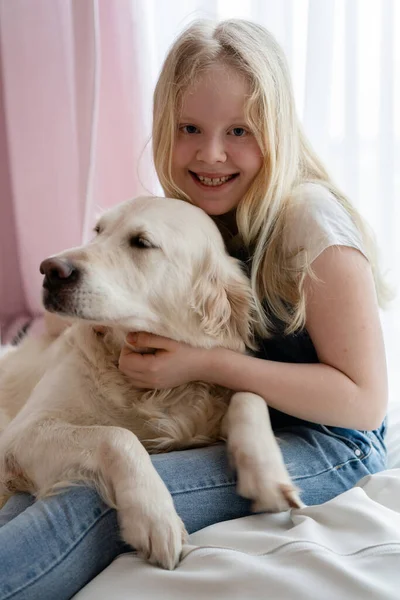 Opieka i miłość do zwierząt domowych. nastolatka dziewczyna w domu przytula z a golden retriever Duży pies — Zdjęcie stockowe