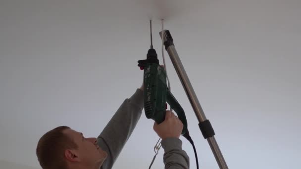 Reparatur und Dekoration. Ein Mann hängt eine Lampe im Raum von der Decke. — Stockvideo