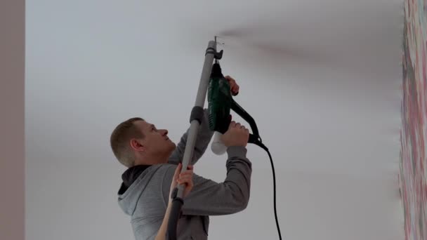 Reparatur und Dekoration. Ein Mann hängt eine Lampe im Raum von der Decke. — Stockvideo