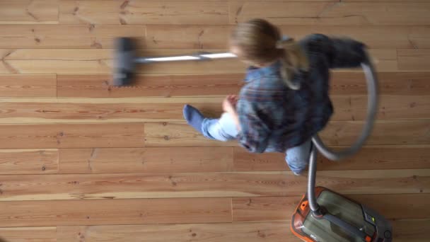 Уборка дома. женщина пылесосит деревянный пол в квартире, вид сверху — стоковое видео