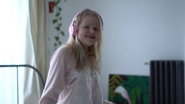 modern life of generation Z. teenage girl in pajamas and headphones in the room on the bed listens to music from a smartphone.