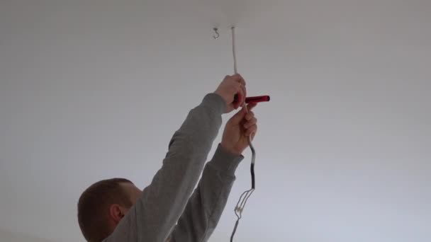 Reparación y decoración del hogar. un hombre cuelga una lámpara en la habitación del techo . — Vídeos de Stock