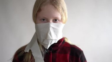 Komik bir video. Koronavirüs salgını yüzünden karantinaya alınmış. Gri arka planda poz veren tuvalet kağıdındaki maskeli kız..