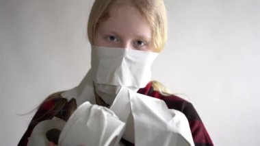 Komik bir video. Koronavirüs salgını yüzünden karantinaya alınmış. Gri arka planda poz veren tuvalet kağıtlarıyla maskeli kız..