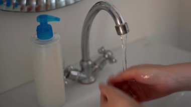 Kadın ellerini banyoda sıvı sabunla yıkıyor..