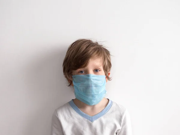 Protección contra el coronavirus. pequeño niño pone una máscara en su cara . — Foto de Stock