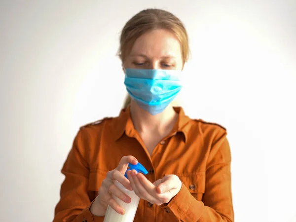 Protección contra el coronavirus. mujer enmascarada trata las manos con antiséptico —  Fotos de Stock