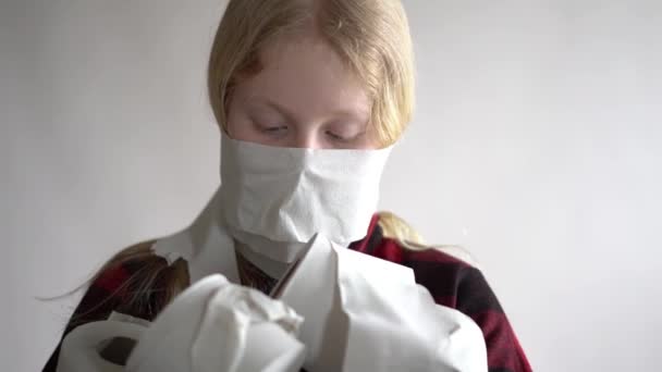 Video divertido - en cuarentena debido a una epidemia de coronavirus. chica enmascarada con rollos de papel higiénico posando sobre fondo gris . — Vídeos de Stock