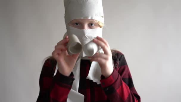 Смешное видео - помещено в карантин из-за эпидемии коронавируса. девушка в маске из туалетной бумаги позирует на сером фоне . — стоковое видео