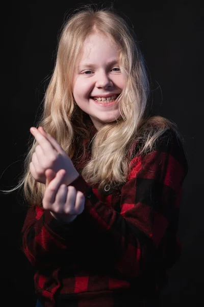 Happy schoolgirl posing in studio on a black background - shows hands signs hearts — Stock Photo, Image