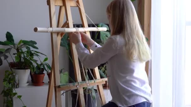 Reste à la maison. travail pendant la quarantaine - une fille dans le salon tissage mural des cordes dans la technique de macramé — Video