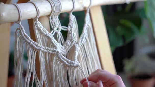 Blijf thuis. werk tijdens de quarantaine - een meisje in de woonkamer muurweven van de touwen in de macrame techniek — Stockvideo