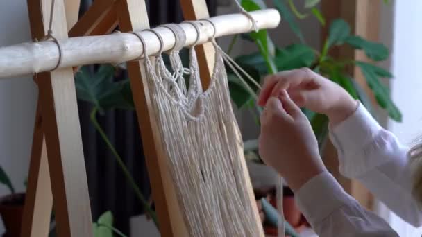 Blijf thuis. werk tijdens de quarantaine - een meisje in de woonkamer muurweven van de touwen in de macrame techniek — Stockvideo