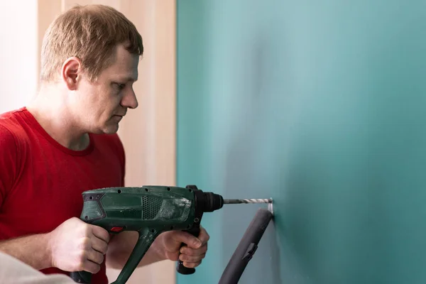 Reparación y decoración. hombre perfora un agujero en la pared Fotos De Stock