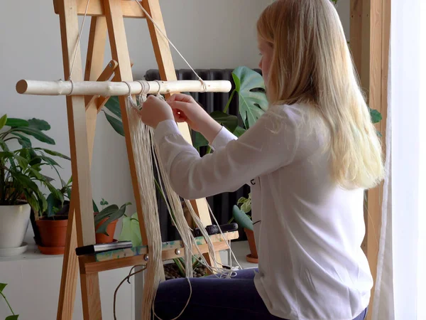 Reste à la maison. travail pendant la quarantaine - une fille dans le salon tissage mural des cordes dans la technique de macramé — Photo