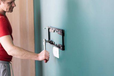 Tamir ve dekorasyon. Bir saatlik hizmet için koca. Bir adam televizyonu duvara bağlar..