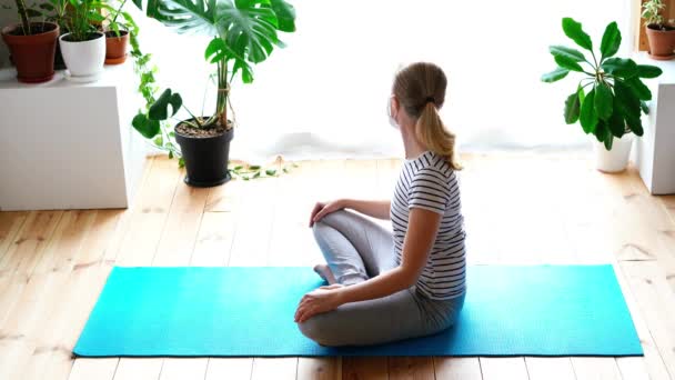 Stanna hemma. maskerad kvinna som gör yoga i vardagsrummet under karantänen — Stockvideo