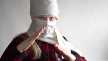 Komik bir video. Koronavirüs salgını yüzünden karantinaya alınmış. Gri arka planda poz veren tuvalet kağıdındaki maskeli kız..