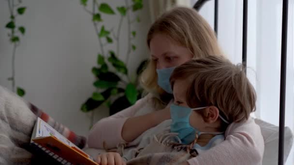 Karantén a koronavírus járvány miatt. Fertőzött álarcos anya és a kisfia az ágyban pihennek a hálószobában.. — Stock videók