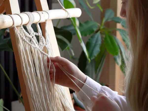 Blijf thuis. werk tijdens de quarantaine - een meisje in de woonkamer muurweven van de touwen in de macrame techniek — Stockfoto