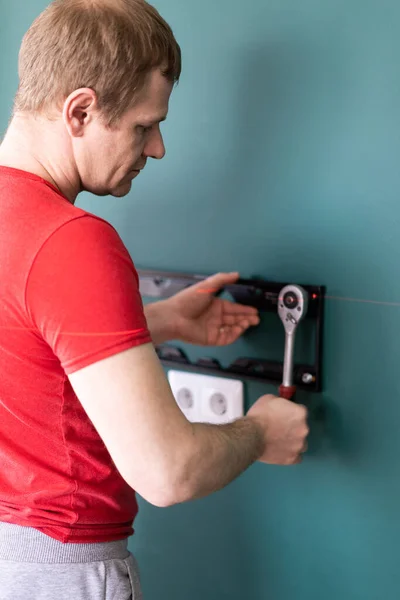 Reparação e decoração. marido por uma hora de serviço. um homem anexa um suporte de TV a uma parede . — Fotografia de Stock