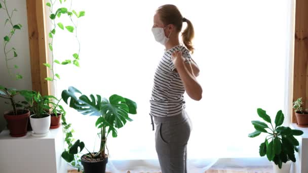 Blijf thuis. gemaskerde vrouw doet yoga in de woonkamer tijdens quarantaine — Stockvideo