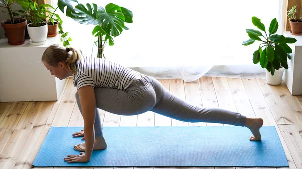 Stanna hemma. maskerad kvinna som gör yoga i vardagsrummet under karantänen — Stockfoto