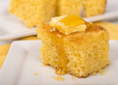 Parçanın cornbread tereyağı ve bal beyaz arka plan bulanık tabağa üst kapalı damlama ile yakın çekim