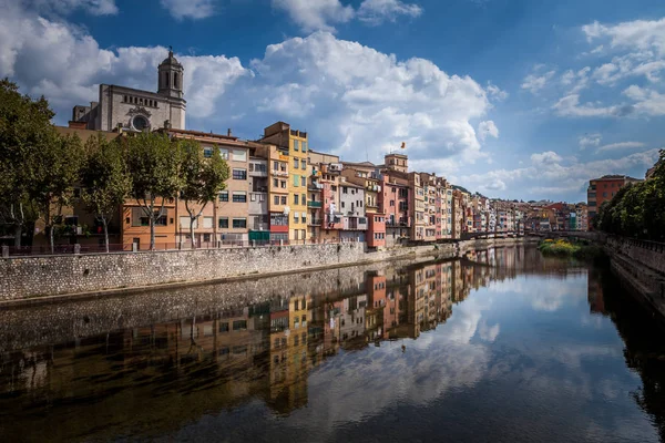 Colorful yellow and orange houses and bridge Pont de Sant Agusti reflected in water river Onyar, in Girona, Catalonia, Spain