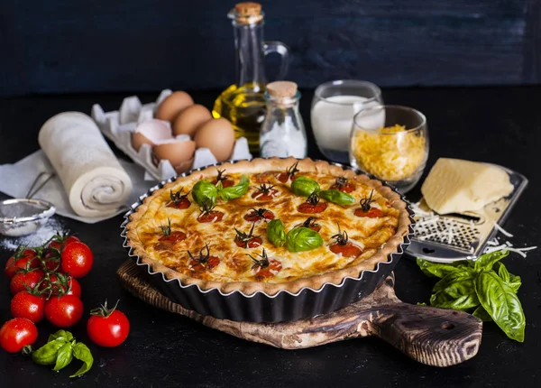 Torta de queijo com tomate e ingredientes de torta na mesa . — Fotografia de Stock