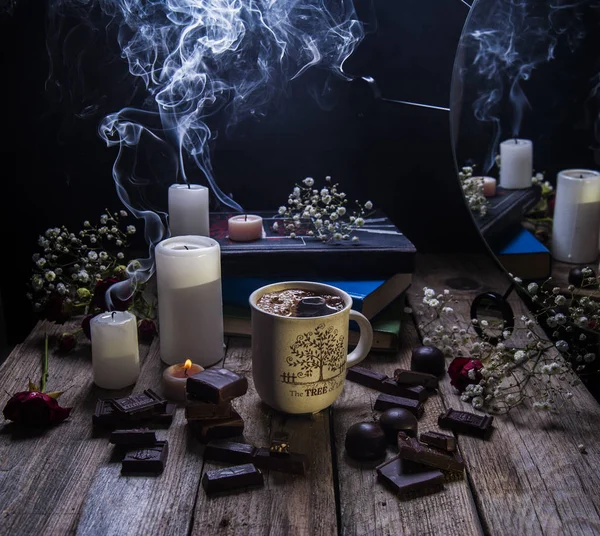 Släckt ljus, en kopp kaffe och choklad på ett träbord. Reflektion i spegeln. — Stockfoto