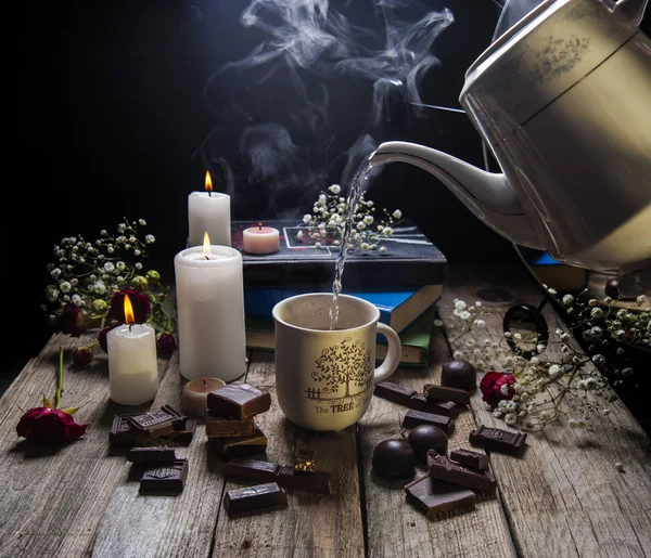 Brinnande ljus, en kopp kaffe och choklad på ett träbord. — Stockfoto