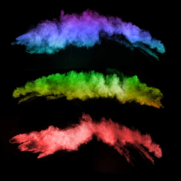 Explosion of colored powders on black background — Stock Photo, Image