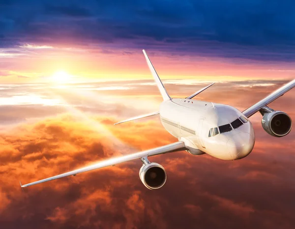 Airplane flying above clouds in dramatic sunset — Stock Photo, Image