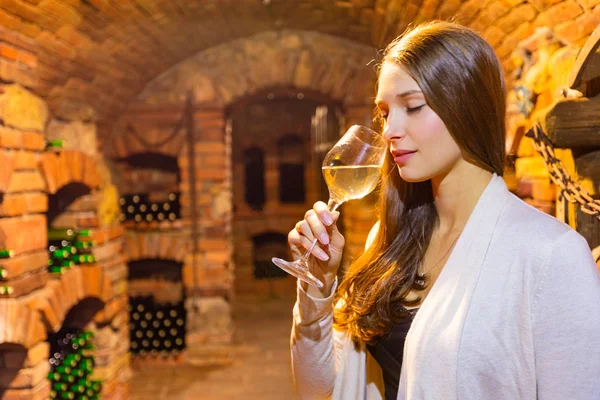 Jeune femme brune dégoulinant du vin en cave — Photo