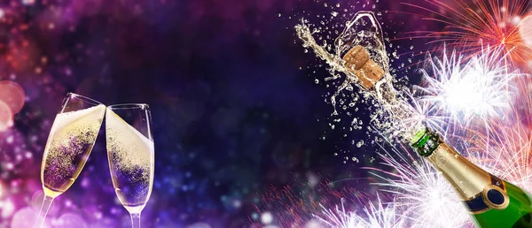 Bottle of champagne with glasses over fireworks background — Stock Photo, Image